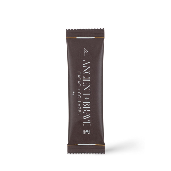 A single-serve sachet of Ancient + Brave Cacao + Collagen Sachets, featuring white text and a geometric logo on a brown background, is photographed on a white surface. This blend combines raw South American cacao with hydrolysed bovine collagen peptides to naturally nourish the skin.