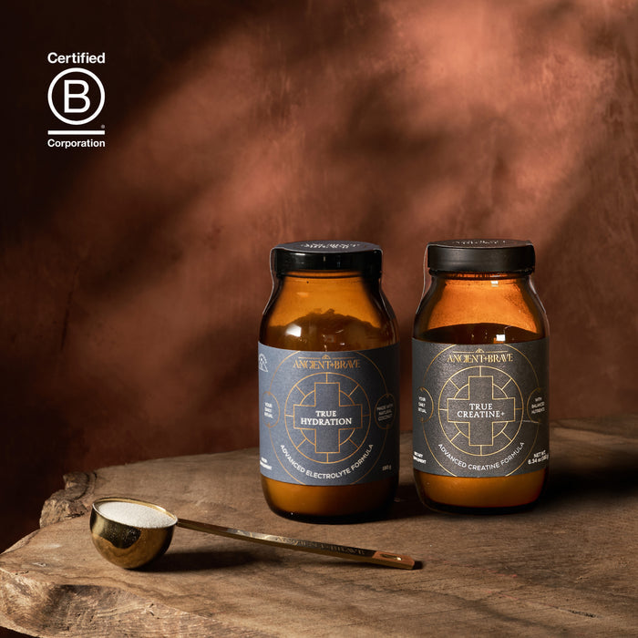 Two bottles of 'Ancient + Brave' on a wooden surface with a dark background