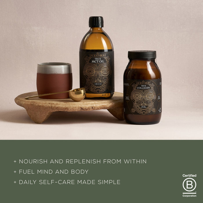 On a stone tray, The Beginner’s Kit by Ancient + Brave is displayed, featuring three bottles and a cup with a wooden lid. The bottles are labeled MCT Oil and True Collagen. Text emphasizes nourishment, fuel for body and mind, and simple daily self-care to support your wellness journey. The B Corp logo appears.