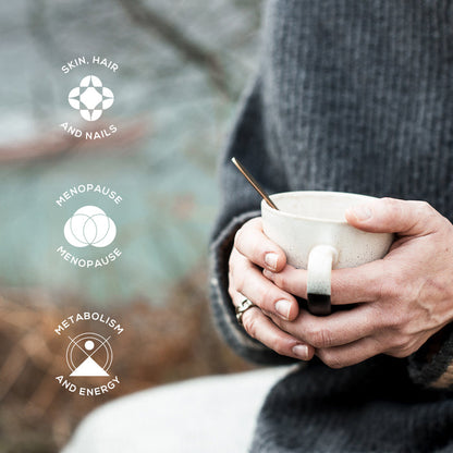 A person in a gray sweater holds a Wild Collagen Sachet mug with both hands. Three icons—Skin, Hair and Nails, Menopause, Metabolism and Energy—show where marine collagen peptides provide support. The background is blurred.
