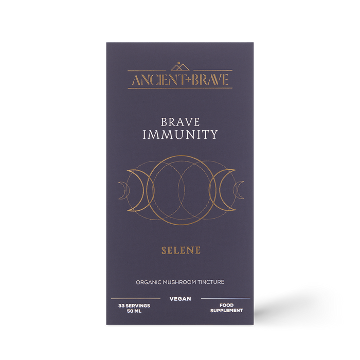 A dark purple box labeled Ancient + Brave Brave Immunity features gold geometric designs. The packaging states that it is an organic mushroom tincture powered by functional mushrooms and organic botanicals, is vegan, and serves as a food supplement designed to help strengthen immunity.