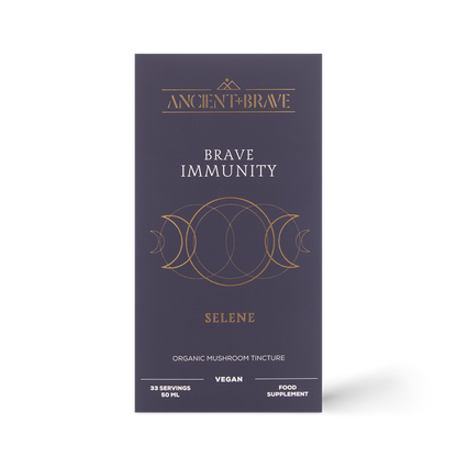 A dark purple box labeled Ancient + Brave Brave Immunity features gold geometric designs. The packaging states that it is an organic mushroom tincture powered by functional mushrooms and organic botanicals, is vegan, and serves as a food supplement designed to help strengthen immunity.
