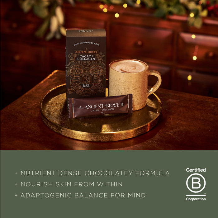 A mug of cocoa and a box containing 10 x Cacao + Collagen Sachets from Ancient + Brave, crafted with South American cacao and hydrolysed bovine collagen, are elegantly arranged on a gold tray. Text highlights the product benefits beside a Certified B Corporation logo, set against a warm, festive backdrop illuminated by twinkling lights.