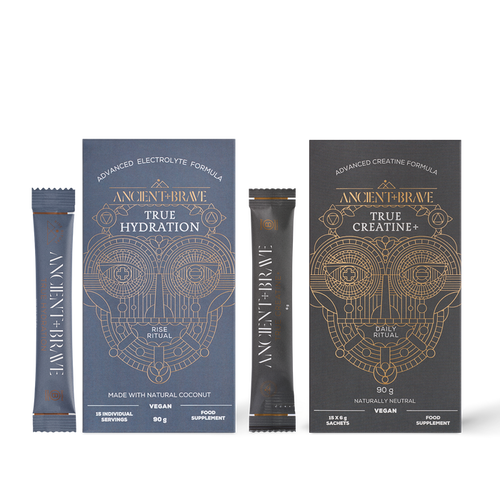 Two Ancient + Brave Recharge Ritual supplement boxes, each with matching stick sachets placed in front, display intricate geometric designs with gold and white text. Featuring an advanced electrolyte formula for enhanced muscle performance, Recharge Ritual is designed to elevate your daily routine.