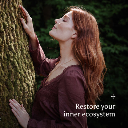 Woman embracing a tree with text 'Restore your inner ecosystem' in a natural setting