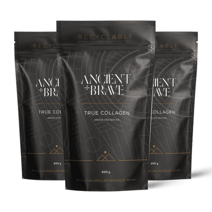 Three stand-up pouches of Ancient + Brave's True Collagen powder arranged in a fan shape against a solid black background. The packaging is dark grey with white text and gold accents.