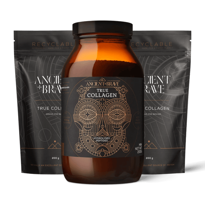 An amber glass jar of Ancient + Brave's True Collagen centered in front of two matching black resealable pouches on a black background. The jar has a black label with gold geometric artwork and text, and the pouches are also black with gold and white text.
