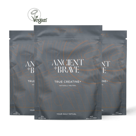 Three stand-up pouches of Ancient + Brave True Creatine+ arranged in a fan shape against a solid black background, with a Vegan logo at the top left.