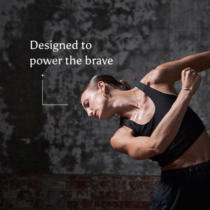 A strong woman in athletic wear poses dynamically against a textured, dark background. Text beside her reads, True Creatine+: Designed to power the brave—with support for muscle health.