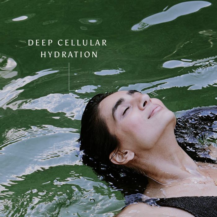 A person floats serenely in green water, eyes closed and smiling, with the text “Deep Cellular Hydration” above them—a tranquil image that radiates wellbeing and hints at the transformative power of Ancient + Brave’s True Hydration - Gift Subscription.