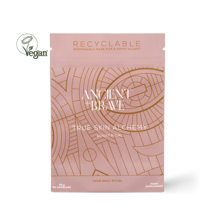 Ancient + Brave True Skin Alchemy Beauty Ritual supplement pouch in a dusty pink color with gold line art patterns, shown on a white background with a Vegan logo overlay.